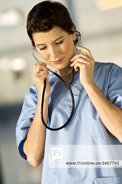 Eine Ärztin setzt sich ein Stethoskop auf die Ohren.