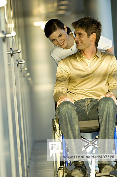 Ärztin schiebt einen männlichen Patienten im Rollstuhl