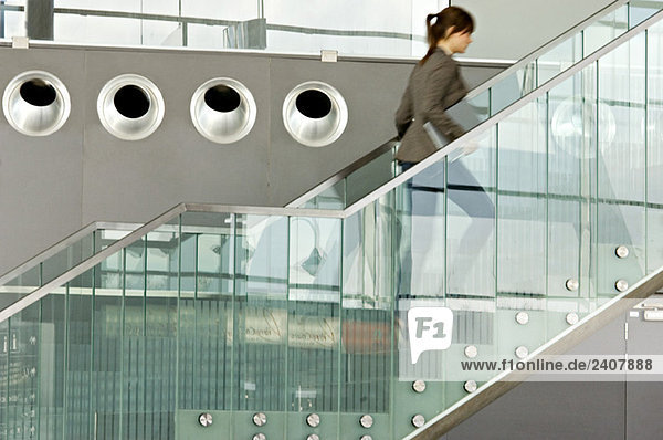 Businesswoman carrying a laptop and moving up on a staircase