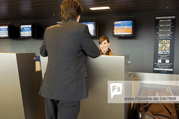 Rear view of a businessman standing at an airport check-in counter