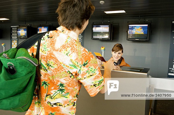 Female airline check-in attendant giving a passport and boarding pass to a passenger