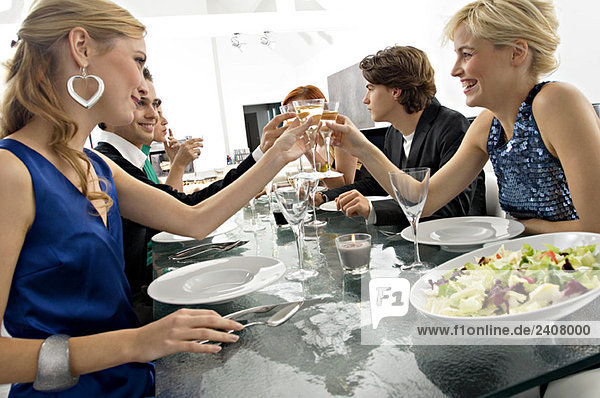 Gruppe von Leuten  die mit Champagner auf einer Dinnerparty anstoßen.