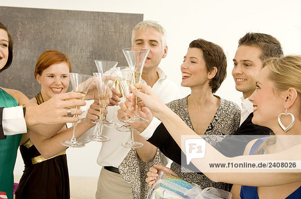 Gruppe von Leuten  die mit Weingläsern auf einer Party anstoßen.