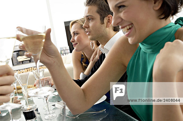 Junge Frau bei einer Dinnerparty mit Champagner anstoßen