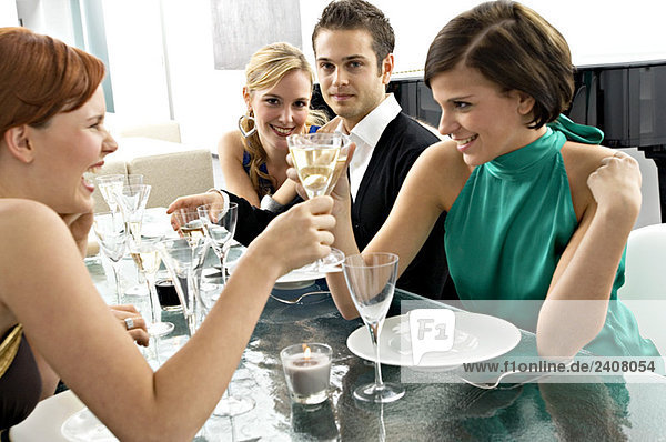 Zwei junge Frauen stoßen mit Champagner auf einer Dinnerparty an.
