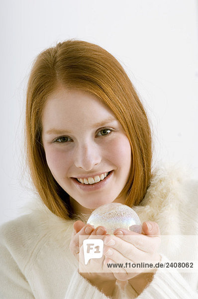 Porträt einer jungen Frau  die eine Kristallkugel hält und lächelt