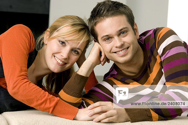 Porträt eines jungen Paares auf einer Couch liegend und lächelnd