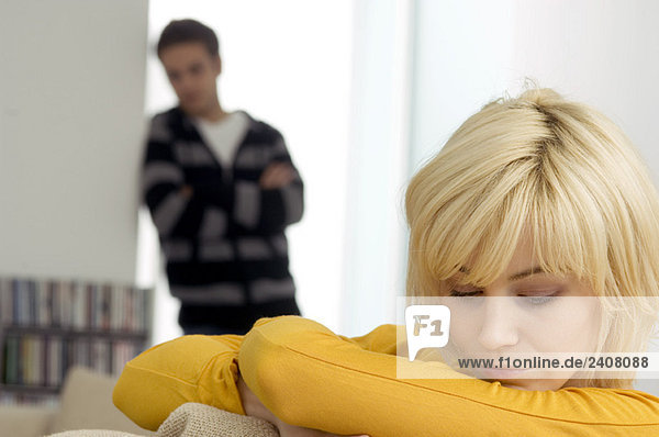Nahaufnahme einer jungen Frau  die traurig aussieht  mit einem jungen Mann im Hintergrund.