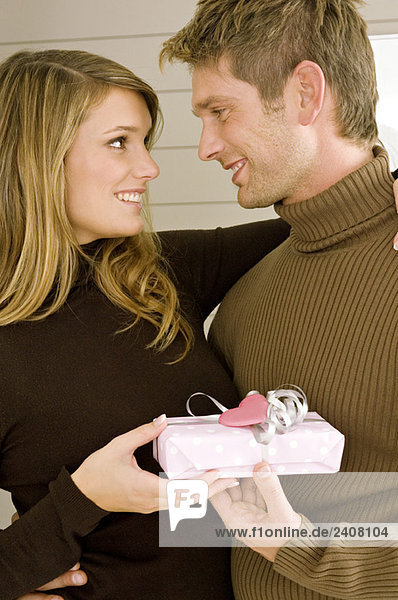 Junge Frau schenkt einem erwachsenen Mann ein Geschenk