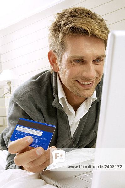 Mid adult man working on a laptop and holding a credit card