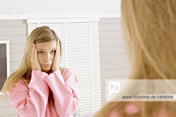 Reflexion einer jungen Frau im Spiegel  die traurig aussieht.
