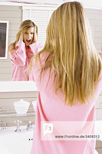 Spiegelung einer jungen Frau  die in den Spiegel schaut und schreit
