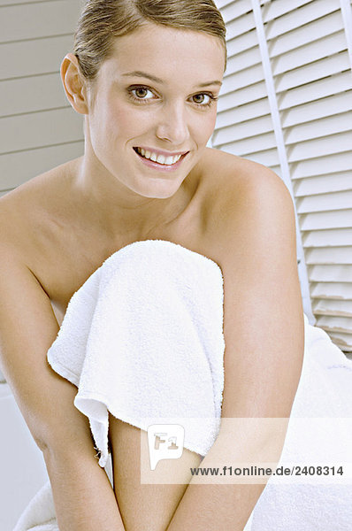 Porträt einer jungen Frau in ein Badetuch gehüllt und lächelnd