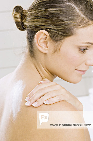 Seitenprofil einer jungen Frau mit Feuchtigkeitscreme auf der Schulter