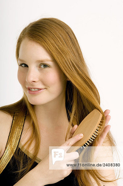 Portrait of a young woman brushing her hair and smiling