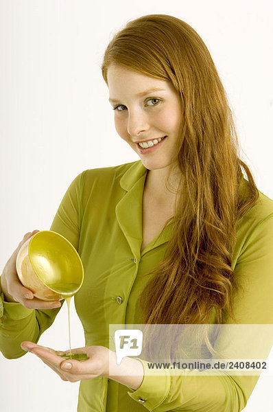Portrait of a young woman pouring massage oil on her palm