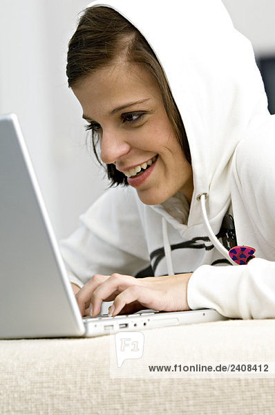 Side profile of a young woman using a laptop and smiling