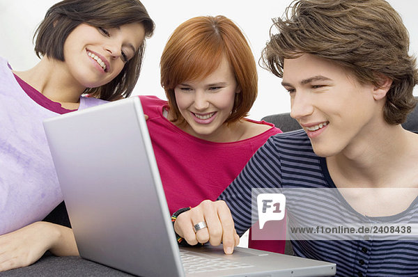 Nahaufnahme von zwei jungen Frauen und einem Teenager mit Blick auf einen Laptop