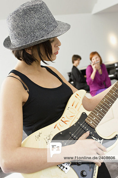 Seitenprofil einer jungen Frau beim Gitarrespielen