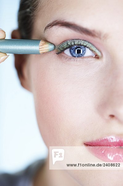 Young woman applying eyeliner