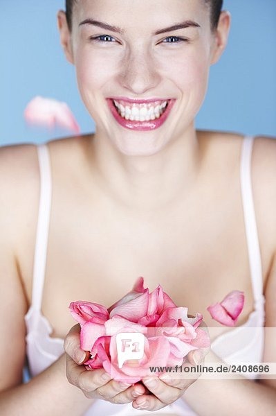 Young smiling woman holding rose petals
