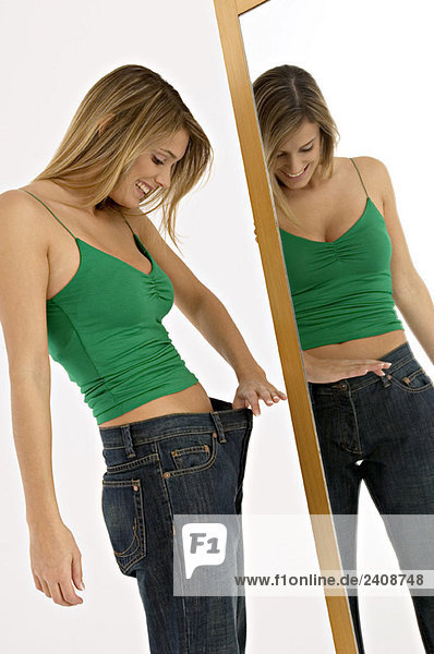 Seitenprofil einer jungen Frau mit Blick auf die Taille vor dem Spiegel