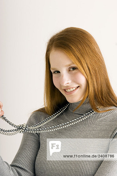 Portrait of a young woman holding her necklace and smiling