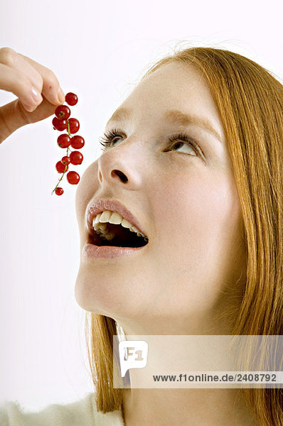 Nahaufnahme einer jungen Frau beim Essen von roten Johannisbeeren