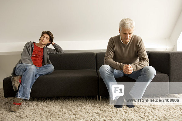 Der reife Mann und sein Sohn sitzen auf einer Couch.