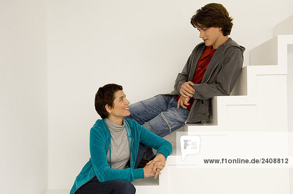 Mid adult woman and her son sitting on a staircase