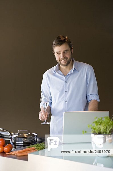 Ein Mann  der einen Laptop benutzt und sich zum Kochen vorbereitet.