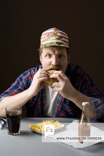 Ein stereotyper Amerikaner  der einen Burger isst.