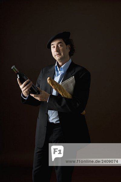 Ein stereotyper Franzose mit einer Flasche Wein  Baguette und einer Zeitung.