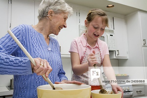 Eine Großmutter und eine Enkelin bereiten Keksteig zu.