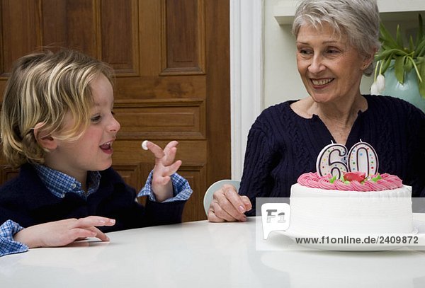 A Senior woman’s grandson eating icing from her birthday cake