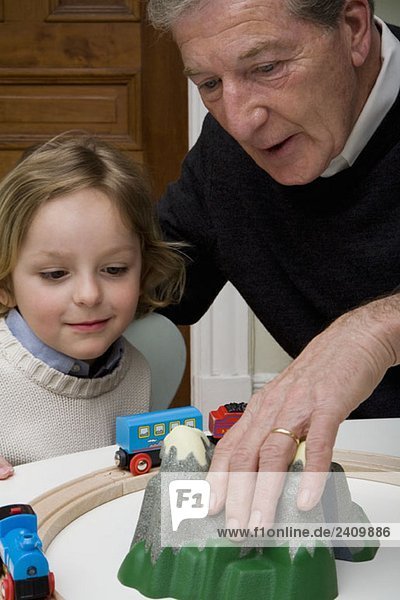 A grandfather and grandson playing with a toy train set