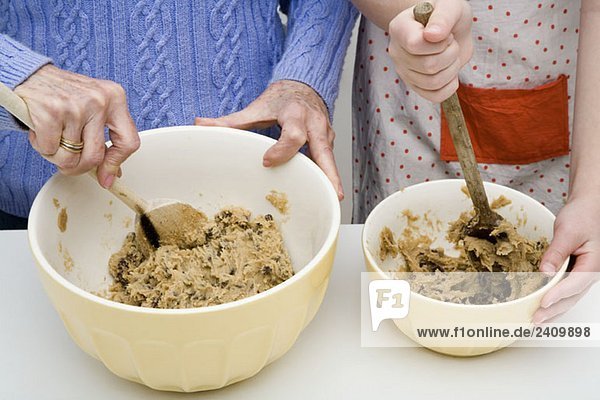 A grandmother and granddaughter preparing cookie dough