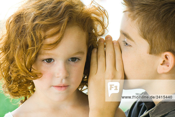 Boy whispering into girl's ear  close-up