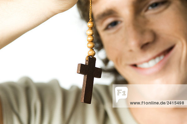 Junger Mann schaut auf das Kreuz  lächelnd  Nahaufnahme