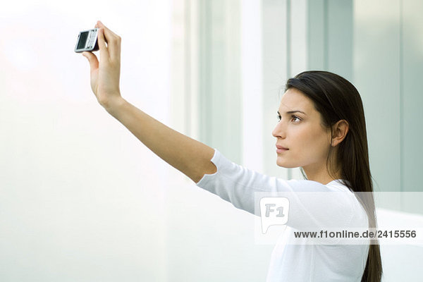 Frau fotografiert sich selbst mit Fotophon  Arm erhoben