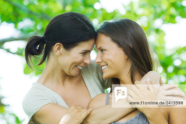 Mother and teen daughter embracing  smiling at each other  touching foreheads
