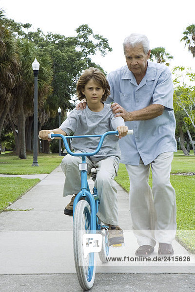 Grandfather teaching boy to ride bicycle  full length