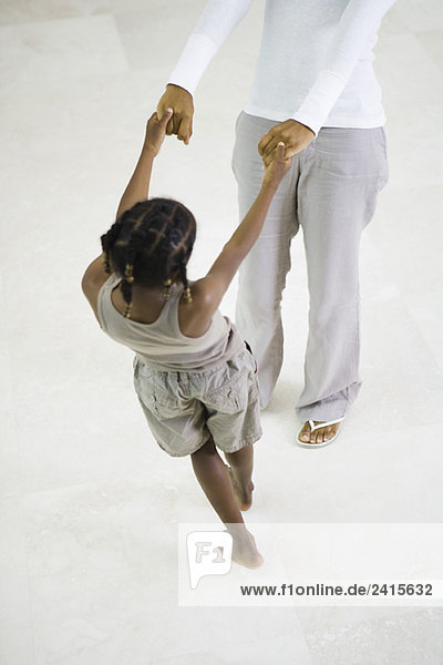 Kleines Mädchen tanzt  hält die Hände der Mutter  Ausschnittansicht