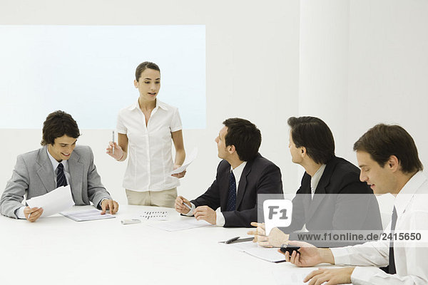 Businesswoman addressing male colleagues at conference table