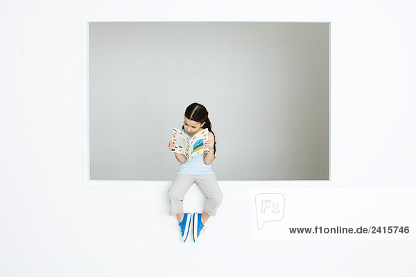 Kleines Mädchen auf dem Sims sitzend  Lesebuch