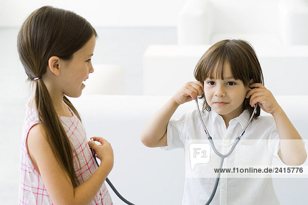 Kleiner Junge hört Mädchenherz mit Stethoskop