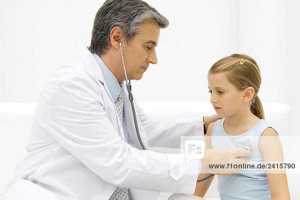 Doctor listening to little girl's heart with stethoscope  side view