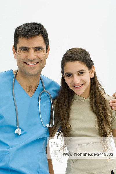 Arzt mit Arm um die Schulter des Mädchens  beide lächelnd vor der Kamera
