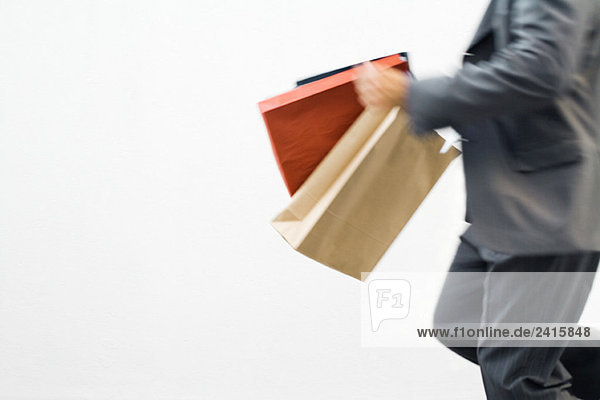 Mann läuft mit Einkaufstaschen  Blick in den Ausschnitt