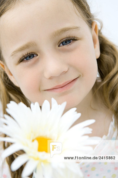 Kopfschuss des Mädchens lächelnd vor der Kamera  Kopf geneigt  Blume im Vordergrund